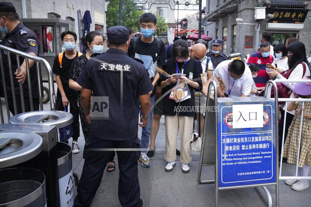 Mark Schiefelbein People scan health check codes with their smartphones to show to a security guard at a tourist shopping street in Beijing, Tuesday, Aug. 3, 2021. Chinese authorities announced Tuesday mass coronavirus testing in Wuhan as an unusually wide series of COVID-19 outbreaks reached the city where the disease was first detected in late 2019. The current outbreaks, while still in the hundreds of cases in total, have spread much more widely than previous ones, reaching multiple provinces and cities including the capital, Beijing. (AP Photo/Mark Schiefelbein)