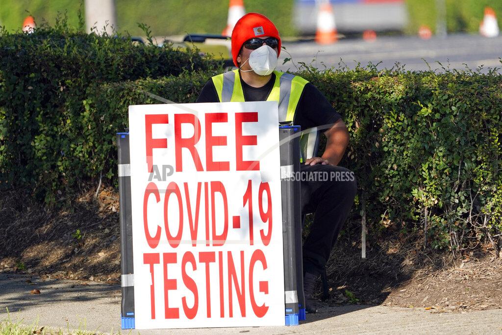 FILE - In this Aug. 19, 2020, file photo, a healthcare worker sits at the entrance to a free COVID-19 testing site at Minute Maid Park in Houston. U.S. health officials have sparked a wave of confusion after posting guidelines that coronavirus testing is not necessary for people who have been in close contact with infected people. (AP Photo/David J. Phillip, File)