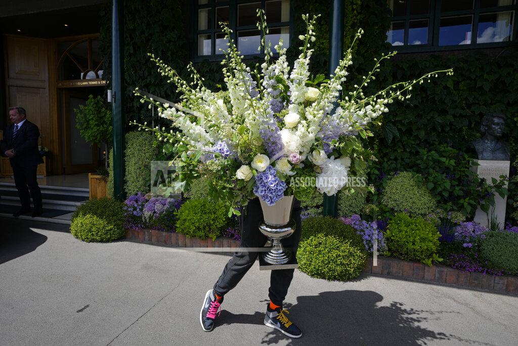 Kirsty Wigglesworth A member of the ground staff moves some flowers ahead of the Wimbledon tennis championships in London, Sunday, June 26, 2022. (AP Photo/Kirsty Wigglesworth)