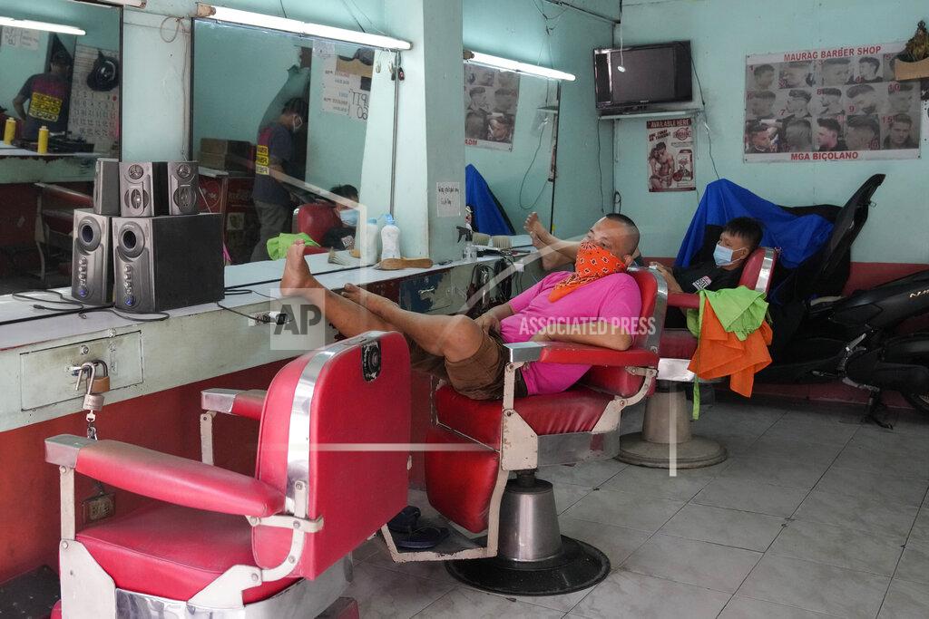 Aaron Favila FILE - In this Sept. 16, 2021, file photo, barbers wait for customers after reopening their shop following easing of COVID restrictions in Quezon city, Philippines. The World Bank on Tuesday, Sept. 28, 2021, cut its economic growth forecast for developing countries in East Asia due to the impact of the coronavirus’s delta variant and called on governments to help the poor and small businesses avoid long-term damage. (AP Photo/Aaron Favila, File)