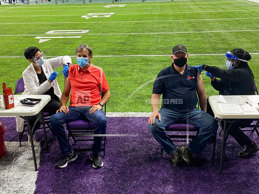 Democratic Minnesota Gov. Tim Walz, second from right, and former Republican Gov. Tim Pawlenty, second from left, receive doses of the single-shot Johnson & Johnson vaccine at a vaccination site at a Minnesota Vikings NFL football team practice facility, Tuesday, March 30, 2021, in Eagan, Minn. The governors received the vaccine on the first day the state expanded eligibility to all Minnesotans 16 and older ahead of an anticipated increase in supply from the federal government. (AP Photo/Mohamed Ibrahim)