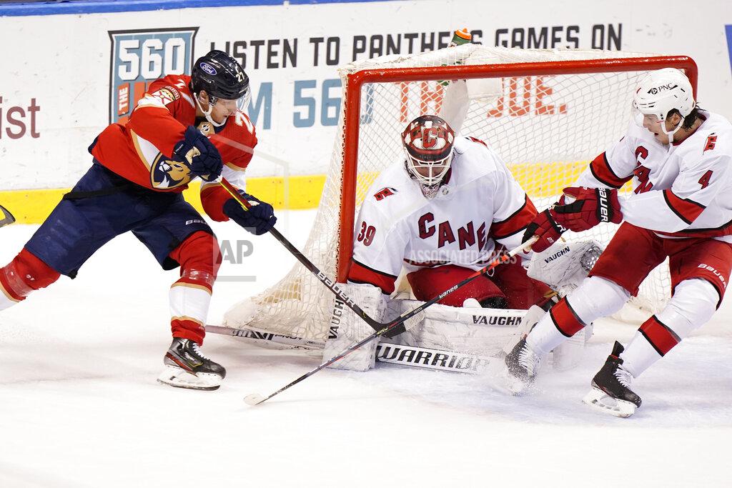 Wilfredo Lee Florida Panthers center Eetu Luostarinen (27) takes a shot against Carolina Hurricanes goaltender Alex Nedeljkovic (39) and defenseman Haydn Fleury (4) during the third period of an NHL hockey game, Monday, March 1, 2021, in Sunrise, Fla. (AP Photo/Wilfredo Lee)
