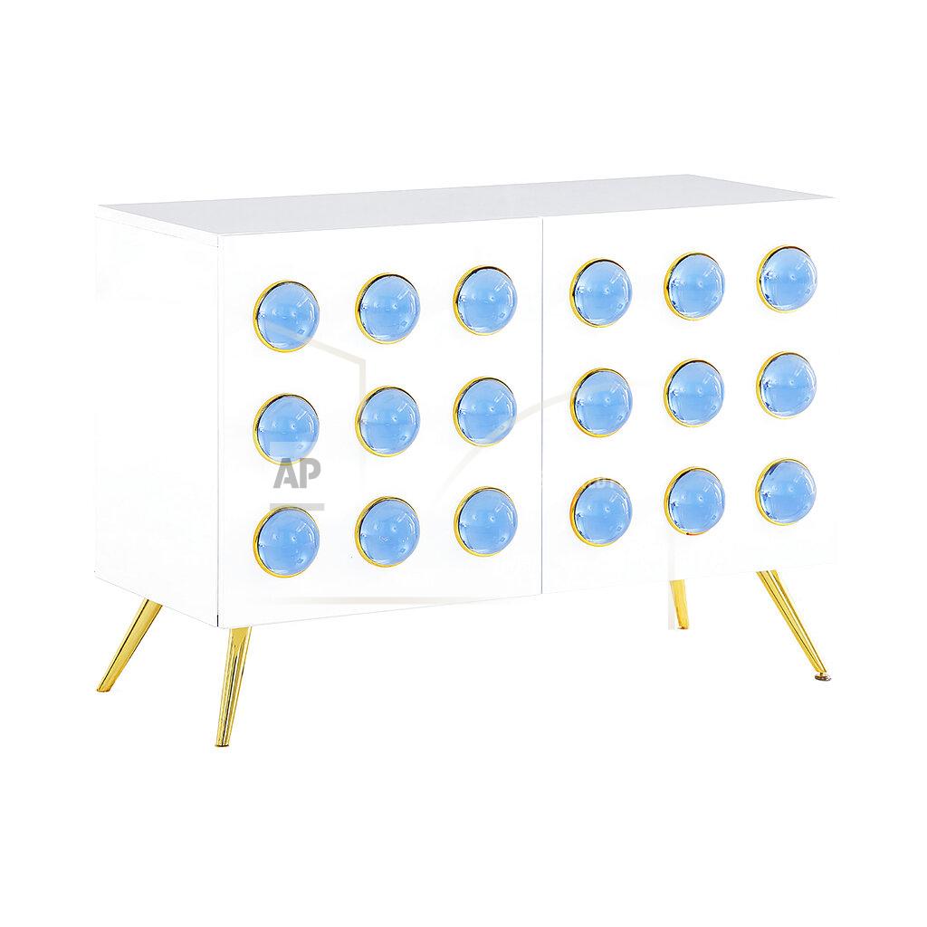 Uncredited Jonathan Adler’s spring collection includes the Globo cabinet, which nods to trending Art Deco. The cabinet is faced with rows of blue acrylic cabochons set in brass, on a white lacquer base. (Jonathan Adler via AP)
