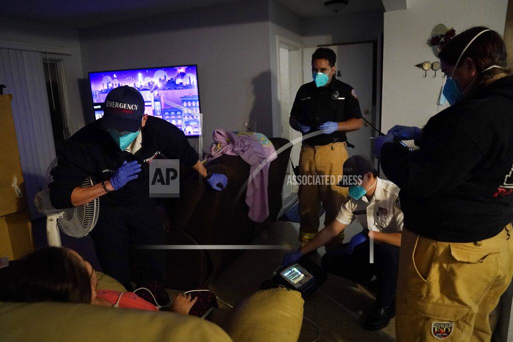 Jae C. Hong A patient is surrounded by emergency medical workers Joshua Hammond, from left, Trenton Amaro, Thomas Hoang and Kim Rose while being treated in her apartment in Placentia, Calif., Saturday, Jan. 9, 2021. EMTs and paramedics have always dealt with life and death — they make split-second decisions about patient care, which hospital to race to, the best and fastest way to save someone — and now they're just a breath away from becoming the patient themselves. (AP Photo/Jae C. Hong)