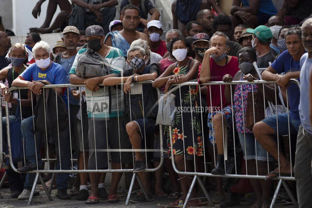 People wait in line for a meal donated by the Leao Xlll Foundation amid the COVID-19 pandemic in Rio de Janeiro, Brazil, Wednesday, April 7, 2021. (AP Photo/Silvia Izquierdo)