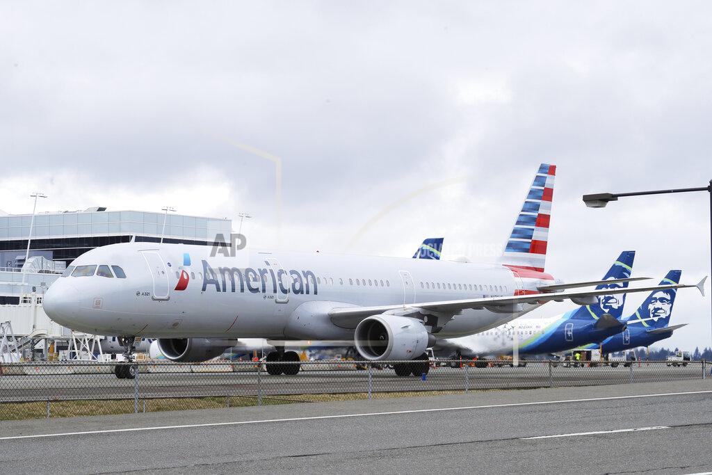 An American Airlines plane taxis past parked Alaska Airlines planes, Thursday, Feb. 13, 2020, at Seattle-Tacoma International Airport in Seattle. American Airlines and Alaska Airlines announced Thursday that they will cooperate more closely on West Coast service, including new American flights from Seattle to India's technology hub in Bangalore. (AP Photo/Ted S. Warren)