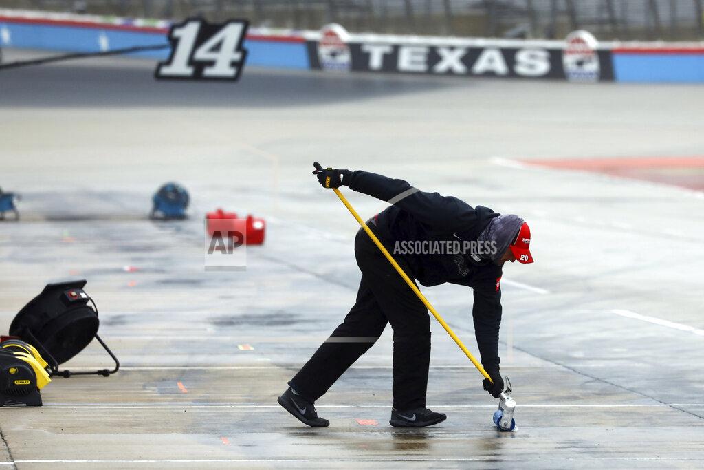 Richard W. Rodriguez A member of Erik Jones pit crew squeegees water out of the pit area as crews prepare to resume a NASCAR Cup Series auto race at Texas Motor Speedway in Fort Worth, Texas, Tuesday, Oct. 27, 2020. The race was stopped on Sunday because of drizzle and misty conditions that allowed drivers to complete just 52 of 334 laps. Another 115 laps have to be completed to get to the halfway mark of 167 laps that would make Texas an official race.. (AP Photo/Richard W. Rodriguez)