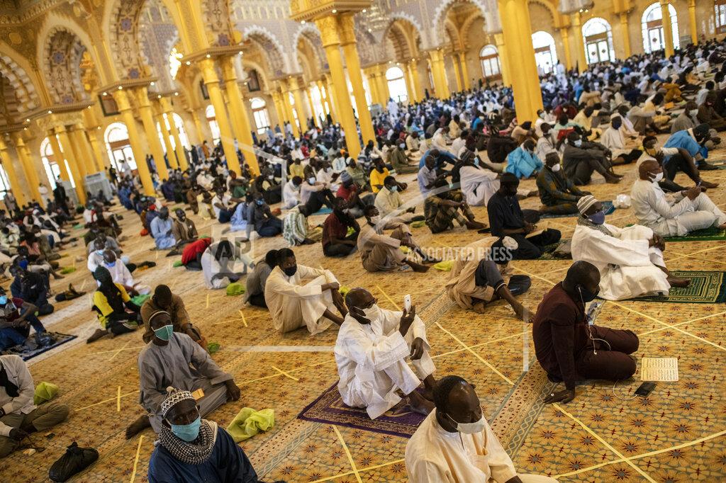 Sylvain Cherkaoui FILE - In this Friday, May 15, 2020 file photo, a follower of the Senegalese Mouride brotherhood, an order of Sufi Islam, films with his smartphone as he and others practice social distancing as they attend Muslim Friday prayers at West Africa's largest mosque the Massalikul Jinaan, after it reopened in Dakar, Senegal. The COVID-19 pandemic is testing the patience of some religious leaders across Africa who worry they will lose followers, and funding, as restrictions on gatherings continue. (AP Photo/Sylvain Cherkaoui, File)