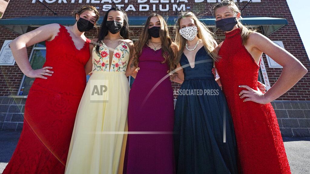 Charles Krupa While wearing their prom gowns, students pose at the ticket box at the New Hampshire Fisher Cats minor league baseball stadium in Manchester, N.H., on Monday, April 26, 2021. After a year without proms, school districts across the country are debating whether they can safely hold an event that many seniors consider a capstone to their high school experience. The nearly 300 student senior class of Manchester's Central High School are waiting to get approval from the city's board of health so they can have their prom at the outdoor venue, due to COVID-19 concerns. (AP Photo/Charles Krupa)