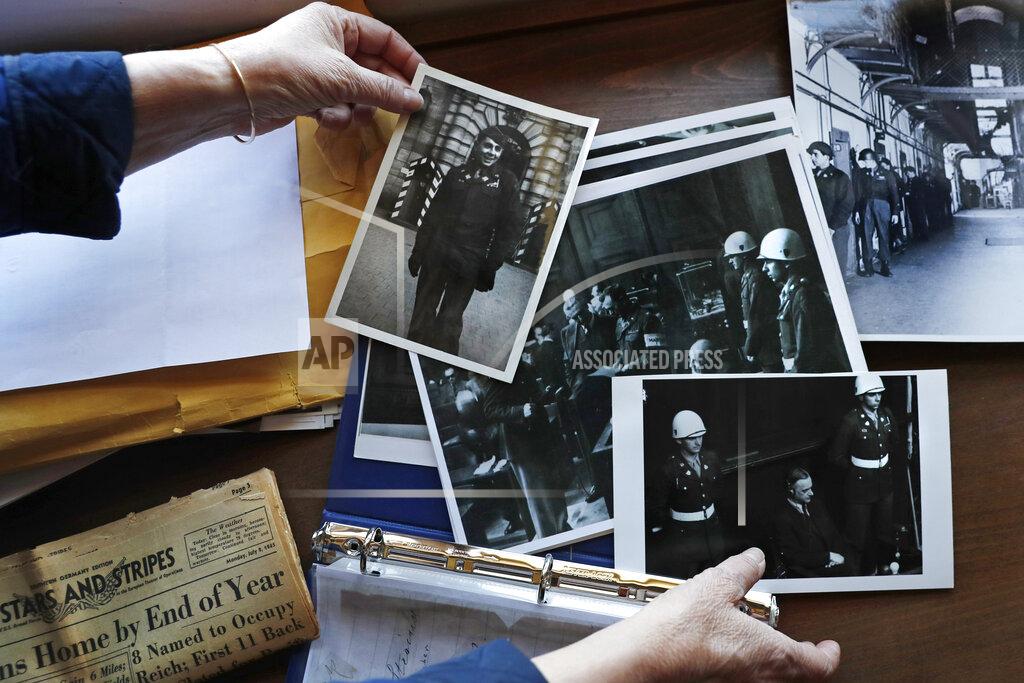 FILE - In this May 13, 2020 file photo, Emily DiPalma Aho looks over photographs and memorabilia of her father, Emilio DiPalma, a World War II veteran, at her home in Jaffrey, N.H. Emilio, who as a 19-year-old U.S. Army infantryman stood guard at the Nuremberg Nazi war crimes trials, died last month at the age of 93 after contracting the coronavirus at Holyoke Soldiers' Home in Massachusetts. The passage of a milestone — 100,000 lives lost due to the coronavirus in the United States — has brought attention to how news organizations are trying to tell the stories behind the numbers. (AP Photo/Charles Krupa, File)