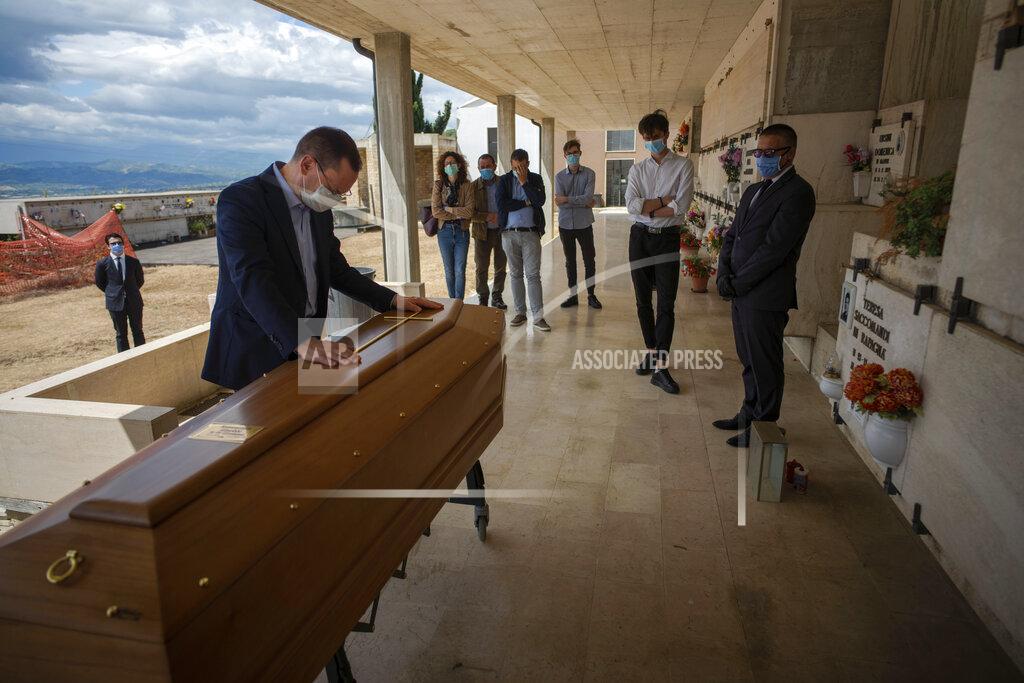 Domenico Stinellis Sabatino Di Girolamo, mayor of Roseto degli Abruzzi, left, lays his hands on the the casket of his mother, Annunziata Ginoble, before her inhumation at the small cemetery of Montepagano, central Italy, Tuesday, May 12, 2020. Under new regulations imposed by the COVID-19 pandemic, only 15 people wearing face masks are allowed to attend funerals and have to respect distancing requirements. (AP Photo/Domenico Stinellis)