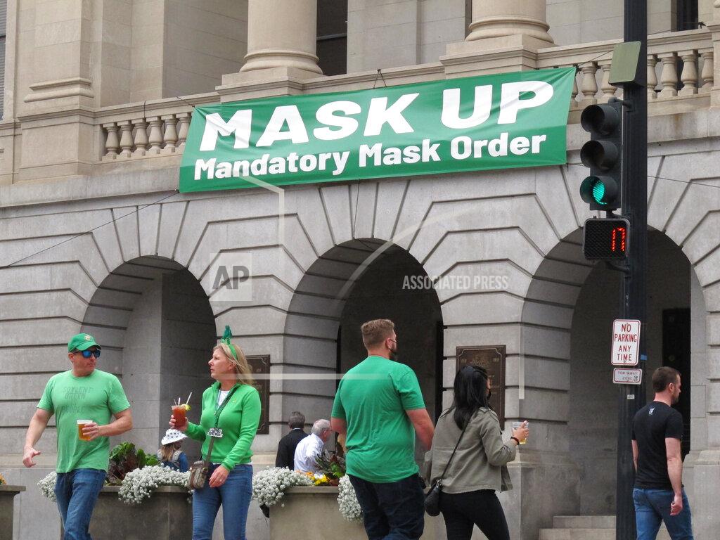 Russ Bynum St. Patrick's Day revelers walk past a large banner urging people to "MASK UP" in front of City Hall in Savannah, Ga., Wednesday, March 17, 2021. Despite its 197-year-old parade being canceled, Savannah still had plenty of tourists for the Irish holiday. Some officials worried the celebration could start an outbreak of the coronavirus. (AP Photo/Russ Bynum)