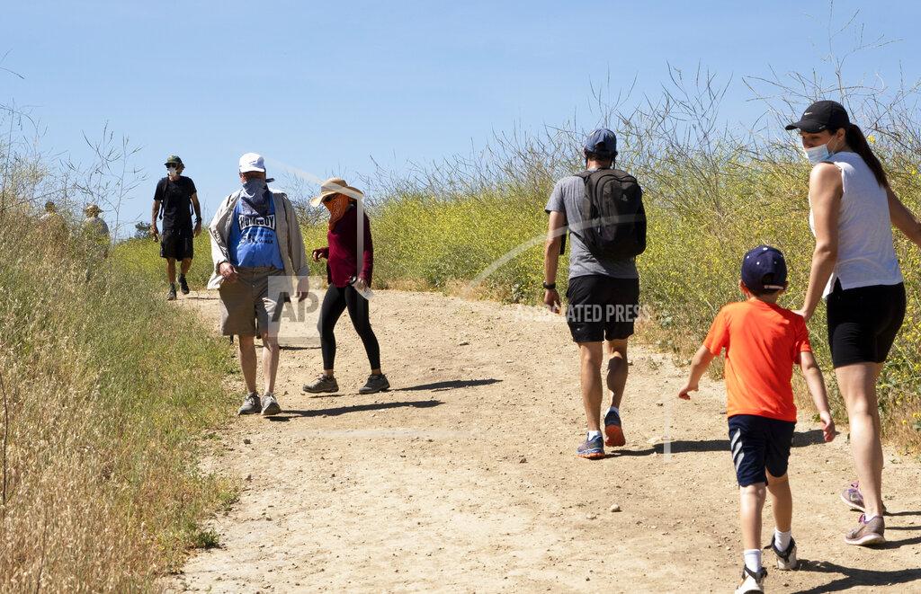 Richard Vogel Visitors wear protective masks and social distance on a walk along a popular hiking trail along the Santa Monica mountain range in the Encino section of Los Angeles, Saturday, May 16, 2020. Leaving home in Los Angeles now requires bringing a face covering, part of the price for reopening more businesses and activities in America's second-largest city, which is moving cautiously as less-populated areas of California press ahead. (AP Photo/Richard Vogel)