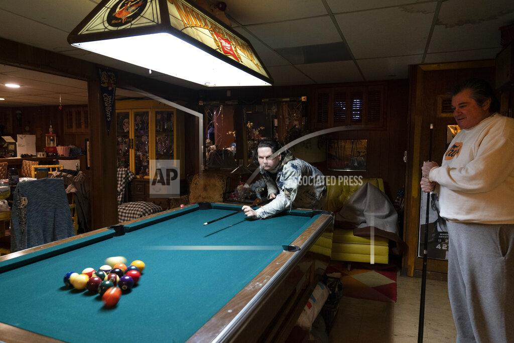 Mark Lennihan Joe DiMeo plays pool with his father John at their home, Thursday, Jan. 28, 2021, in Clark, N.J., six months after an extremely rare double hand and face transplant. Back in 2018, DiMeo fell asleep at the wheel, he said, losing control of his car, which hit a curb and utility pole, flipped over, and burst into flames. (AP Photo/Mark Lennihan)