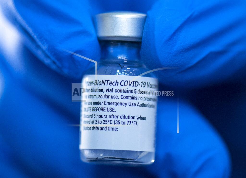 Boris Roessler A pharmacist holds a vial of Pfizer-Biontech's Corona vaccine at the opening of the vaccination center in the Festhalle in Frankfurt, Germany, Tuesday, Jan.19, 2021. The state of Hesse operates one of its vaccination centers where thousands of people usually gather at concerts and trade fairs. (Boris Roessler/dpa via AP)