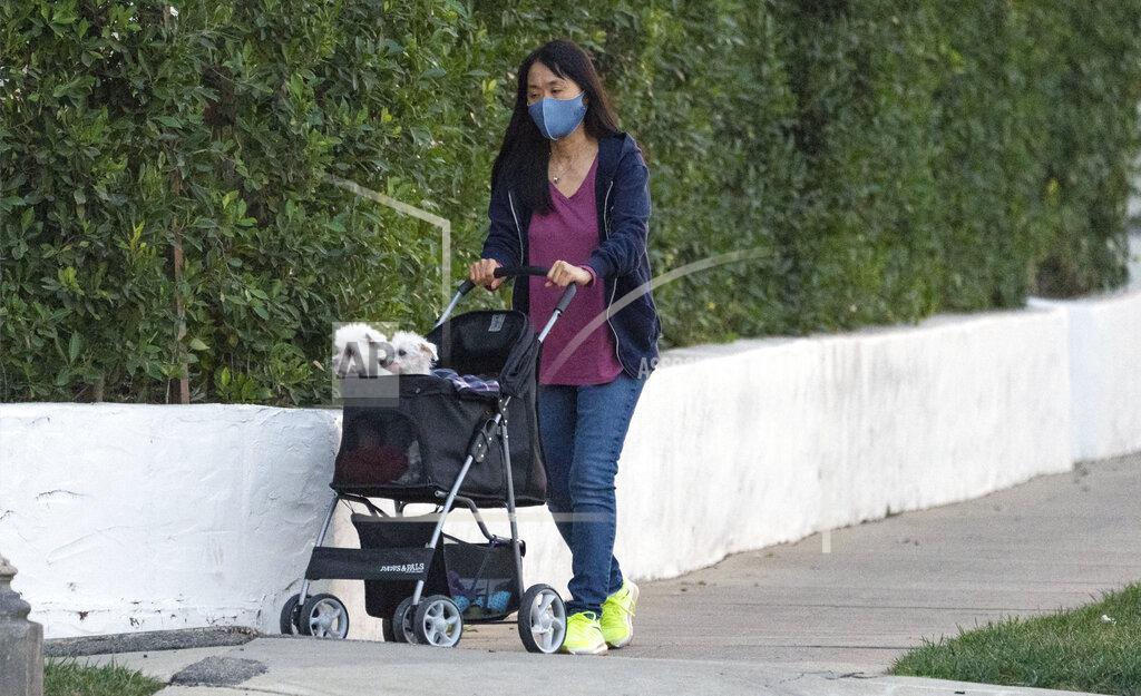 Damian Dovarganes A woman wears a mask as she takes two small dogs in a stroller for a walk in Los Angeles Thursday, Jan. 7, 2021. California health authorities reported Thursday a record two-day total of 1,042 virus deaths, with many people infected during the surge after Halloween and Thanksgiving. The California Hospital Association says the state is moving too slowly to find ways to handle so many cases. (AP Photo/Damian Dovarganes)