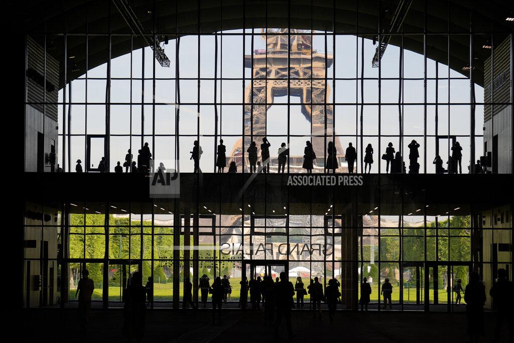 Francois Mori FILE - In this Wednesday, June 9, 2021 file photo, visitors gather during a presentation visit of the "Grand Palais Ephemere", with the Eiffel Tower in the background, in Paris. For Europe’s battered tourism industry, fresh virus outbreaks and chaos and confusion over travel rules are contributing to a another cruel summer. With COVID-19 variants surging in parts of Europe, popular destination countries are taking measures to contain outbreaks. (AP Photo/Francois Mori, File)