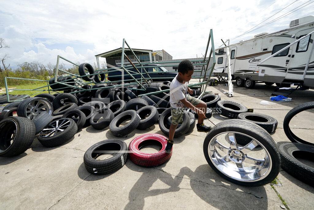 Gerald Herbert Cameron Arvie, 11, climbs on tires strewn by Hurricane Laura, at the family's destroyed auto detailing business in Lake Charles, La., in the aftermath of Hurricane Laura, Sunday, Aug. 30, 2020. (AP Photo/Gerald Herbert)