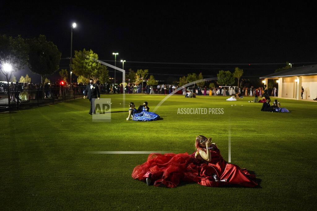 Paul Ratje Julie Lattang, 18, and Brianna Cazadillas, 17, laugh with each other on a field while attending prom at the Grace Gardens Event Center in El Paso, Texas on Friday, May 7, 2021. Around 2,000 attended the outdoor event at the private venue after local school districts announced they would not host proms this year. Tickets cost $45. (AP Photo/Paul Ratje)