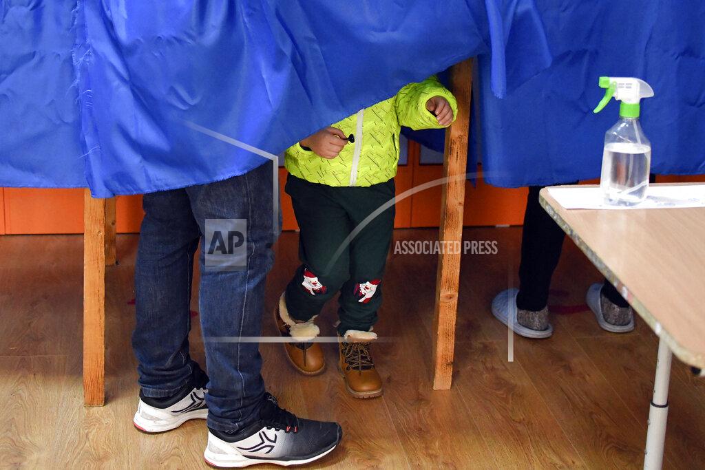Andreea Alexandru A child holds a voting stamp in the village of Branesti, Romania, Sunday, Dec. 6, 2020. Voting started in Romania's legislative election expected to restore some measure of stability after five years of political and social turbulence with more than 18 million Romanians registered to vote for a new legislative body. (AP Photo/Andreea Alexandru)