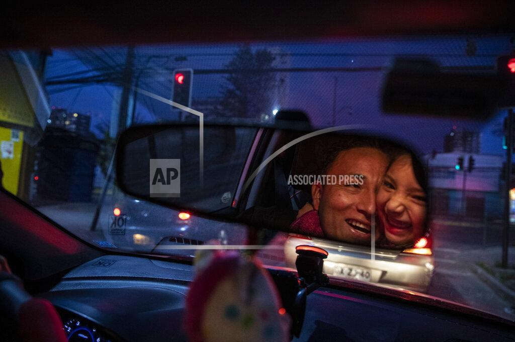 Esteban Felix Reflected in the rearview mirror, Jose Collantes gets a hug from daughter Kehity while they're stopped at a red light, as Jose drives his five-year-old home from a playdate in Santiago, Chile, Sunday, Sept. 6, 2020, three months after they lost his wife, her mother, to COVID-19. Their case highlights how COVID-19 deaths the world over are often the beginning of a new personal journey for those affected. (AP Photo/Esteban Felix)