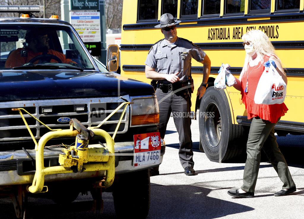 Warren Dillaway Ohio State Highway Patrol Sgt. Larry Johnson, left, assists Ashtabula Area City Schools employees, including, Tina McCoy at a meal delivery site along Route 20 in Ashtabula, Ohio, on Thursday April 2, 2020, morning. (Warren Dillaway/The Star-Beacon via AP)