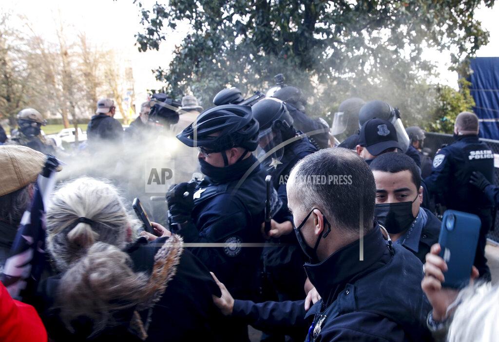 Abigail Dollins FILE - In this Dec. 21, 2020, file photo, protesters spray mace toward police as they attempt to get into the Oregon State Capitol during a special session of the state legislature in Salem, Ore. When President Trump-supporting insurrectionists stormed the U.S. Capitol in an attempt to overturn the presidential election on Wednesday, Jan. 6 2021 the nation was shocked, but not unwarned. A series of dress rehearsals of sorts have played out in statehouses in Michigan, Oregon, Idaho and elsewhere in recent months, with armed protesters forcing their way into buildings.(Abigail Dollins/Statesman-Journal via AP)