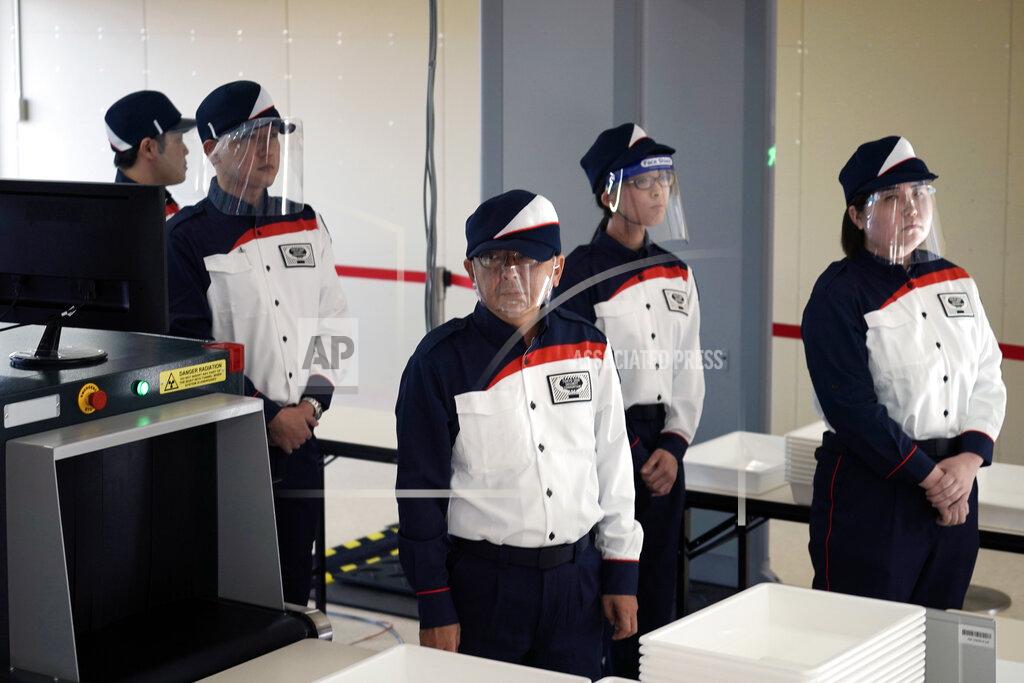 Staff members wearing face shields participate in a screening test for spectators and officials to ensure a safe and secure Toyo Olympic Games Wednesday, Oct. 21, 2020, in Tokyo. Tokyo Olympic officials say they don't know exactly what measures will be taken against the COVID-19 pandemic at next year's Games, but they want the world to know they're working on it. (AP Photo/Eugene Hoshiko)