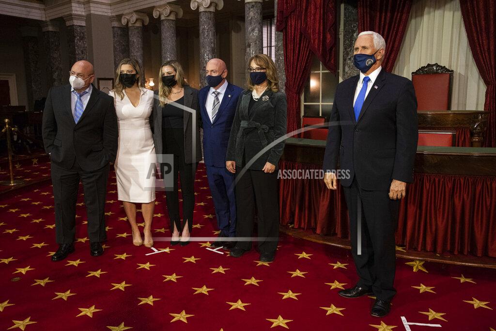 Graeme Jennings Sen. Mark Kelly, D-Ariz., third from right, poses for a photo with from left, his brother Scott Kelly, daughters Claire Kelly and Claudia Kelly, wife former Rep. Gabby Giffords, D-Ariz., and Vice President Mike Pence, in the Old Senate Chamber on Capitol Hill in Washington, Wednesday, Dec. 2, 2020, after participating in a re-enactment of his swearing-in. (Graeme Jennings/Pool via AP)