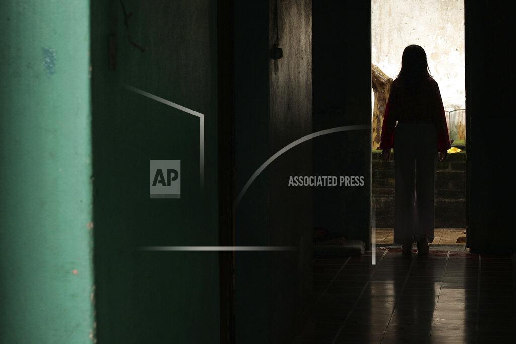 A Salvadoran businesswoman, who is one of the applicants of a small refugee program that was shut down by President Donald Trump, stands in a hallway of her home in Santa Ana, El Salvador, Saturday, Aug. 22, 2020. After a court settlement and a judge order, however, she and about 2,700 other Central Americans who had been conditionally approved, have been allowed to move forward in the process and travel to the U.S. The woman is now waiting to finally join her husband and daughter in the U.S. but the new coronavirus pandemic has delayed her arrival. (AP Photo/Salvador Melendez)