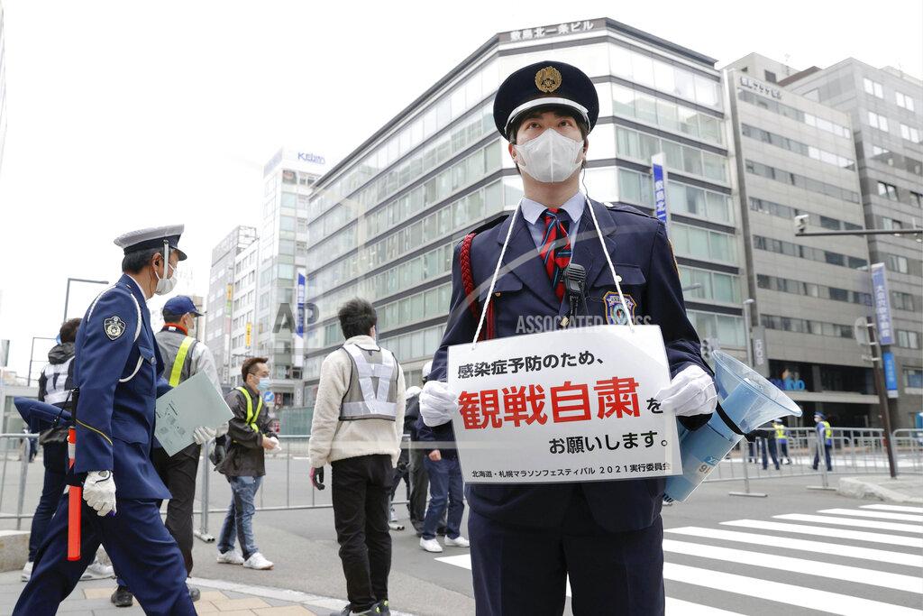 Masanori Takei A security guard stands with a note calling for refraining from watching a half-marathon to help curb the spread of the coronavirus in Sapporo, northern Japan, Wednesday, May 5, 2021. The half-marathon was held as a Tokyo 2020 test event three months before the Olympics open. (Masanori Takei/Kyodo News via AP)
