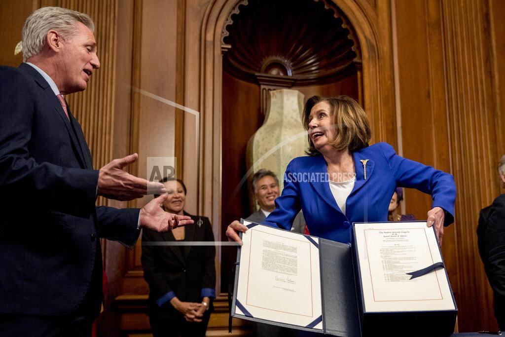 House Speaker Nancy Pelosi of Calif., right, speaks with House Minority Leader Kevin McCarthy of Calif., left, as she holds up the Coronavirus Aid, Relief, and Economic Security (CARES) Act after signing it on Capitol Hill, Friday, March 27, 2020, in Washington. The $2.2 trillion package will head to head to President Donald Trump for his signature. (AP Photo/Andrew Harnik)