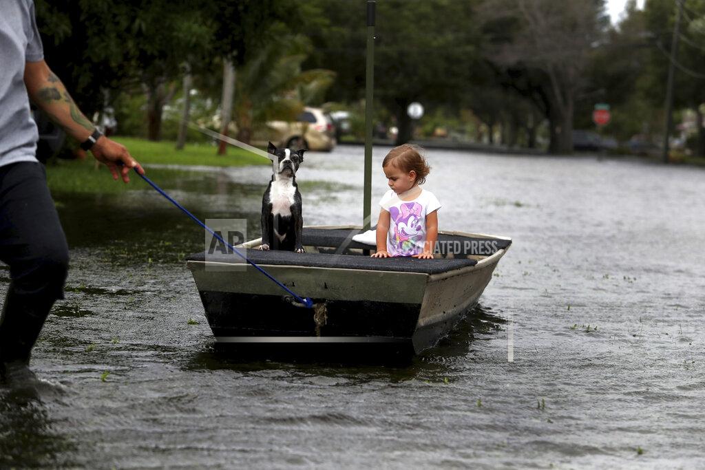 Carline Jean Lemay Acosta pulls his daughter Layla, 2, and dog Buster on a boat as they tour his flooded neighborhood in Plantation, Fla., on Monday, Nov. 9, 2020, a day after Tropical Storm Eta made landfall in the Florida Keys and flooded parts of South Florida. (Carline Jean/South Florida Sun-Sentinel via AP)