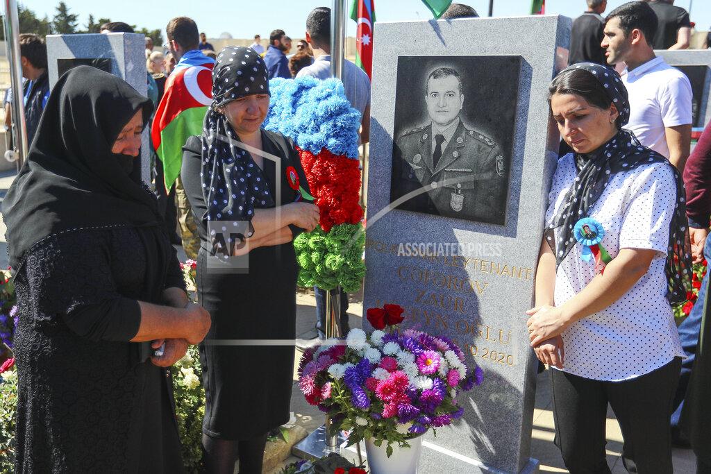 Aziz Karimov Relatives mourn near a grave of killed Azerbaijan's army soldier at a military cemetery with the graves of the fallen soldiers during the during the fighting over Nagorno-Karabakh in 2020 year, outside Baku, Azerbaijan, Monday, Sept. 27, 2021. Azerbaijan and Armenia are marking the first anniversary of the start of their six-week war in which more than 6,600 people died and that ended with Azerbaijan regaining control of large swaths of territory. Soldiers carrying photos of comrades killed in the war marched Monday through the center of the Azerbaijaini capital Baku. (AP Photo/Aziz Karimov)
