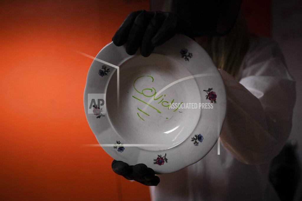 Jae C. Hong Asia Made, 50, shows a plate with the word "COVID" written on it before smashing it into a wall in a rage room at Smash RX LLC in Westlake Village, Calif., Friday, Feb. 5, 2021. (AP Photo/Jae C. Hong)