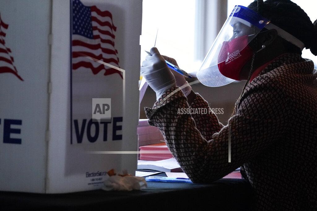 Brynn Anderson FILE - In this Nov. 3, 2020, file photo, a poll worker talks to a voter before they vote on a paper ballot on Election Day in Atlanta. In addition to their nationwide efforts to restrict voting access, Republican lawmakers in some key states are seeking greater control over the local mechanics of elections, from voter registration to certifying results. It's part of a broader GOP campaign to limit access to the ballot and challenge outcomes. (AP Photo/Brynn Anderson, File)