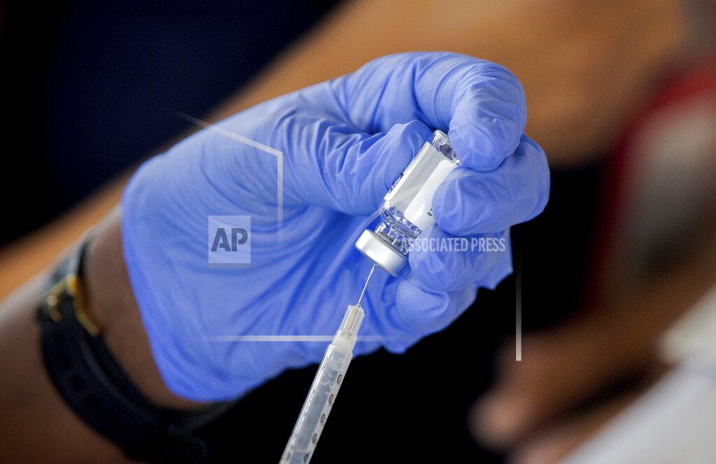 An employee with the LA Dept. of Health fills a J&J shot during a drive-through shot give-away with the help of the Louisiana National Guard at the St. Tammany Parish Fair Grounds in Covington, La., Friday, April 9, 2021. (David Grunfeld/The Advocate via AP)