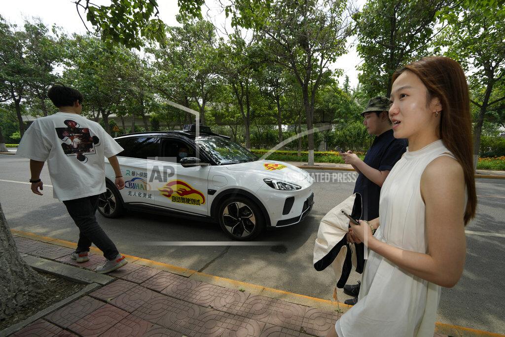 Ng Han Guan Workers prepare to catch a ride with a self-driving taxi developed by tech giant Baidu Inc. on June 14, 2022, in Beijing. Baidu Inc. is China's highest-profile competitor in a multibillion-dollar race with Alphabet Inc.'s Waymo and General Motors Co.'s Cruise to create self-driving cars. (AP Photo/Ng Han Guan)