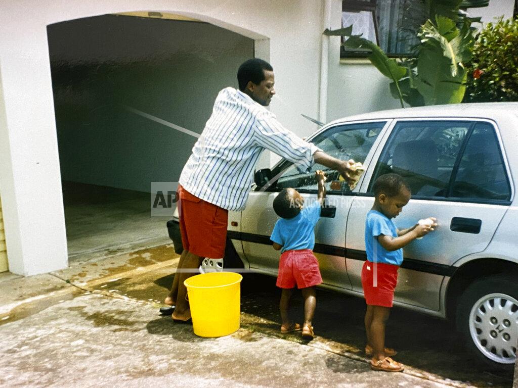 Uncredited In this photo supplied courtesy of the Mini family, the late South African doctor and activist Dr. Clarence Mini, washes his car with his children in the early 1990's. Clarence Mini, a South African activist and doctor who died of COVID-19 spent his life fighting apartheid, the government's denial of HIV/AIDS and rampant corruption. Loved ones say Mini knew the odds were against him but he was committed to what he believed was right. He died in May at age 69. (Photo courtesy of the Mini family via AP)