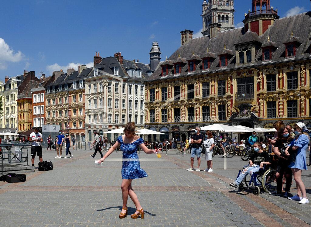 Michel Spingler FILE - In this June 6, 2021, file photo, a woman dances by a cafe terrace in Lille, northern France. In France, authorities said it’s no longer always mandatory to wear masks outdoors and said they would end a nightly coronavirus curfew this weekend. (AP Photo/Michel Spingler, File)