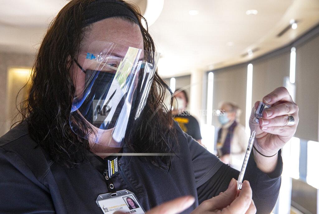 Andy Abeyta Staff nurse Rachel Lewis draws a dose of the Pfizer-BioNTech COVID-19 vaccine from a vial for a nurse at the University of Iowa Hospitals and Clinics, Monday, Dec. 14, 2020, in Iowa City, Iowa. (Andy Abeyta/The Gazette via AP)