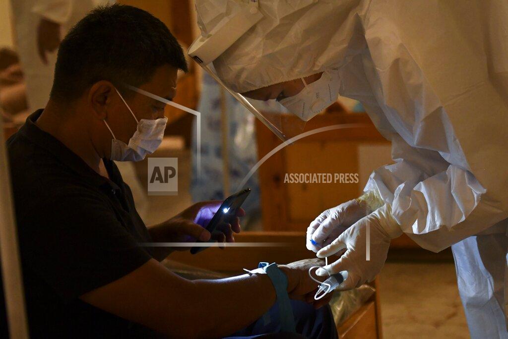 Vladimir Voronin A medical worker places an intravenous drip for a patient who is suspected of having the coronavirus as he lights an area with his phone in a restaurant converted to a clinic in Bishkek, Kyrgyzstan, Wednesday, July 22, 2020. The restaurant is being used as night-time clinic to support the country's health care system, struggling with the coronavirus outbreak. Doctors and nurses from other facilities work there and treat people between 8 p.m. and 8 a.m. (AP Photo/Vladimir Voronin)