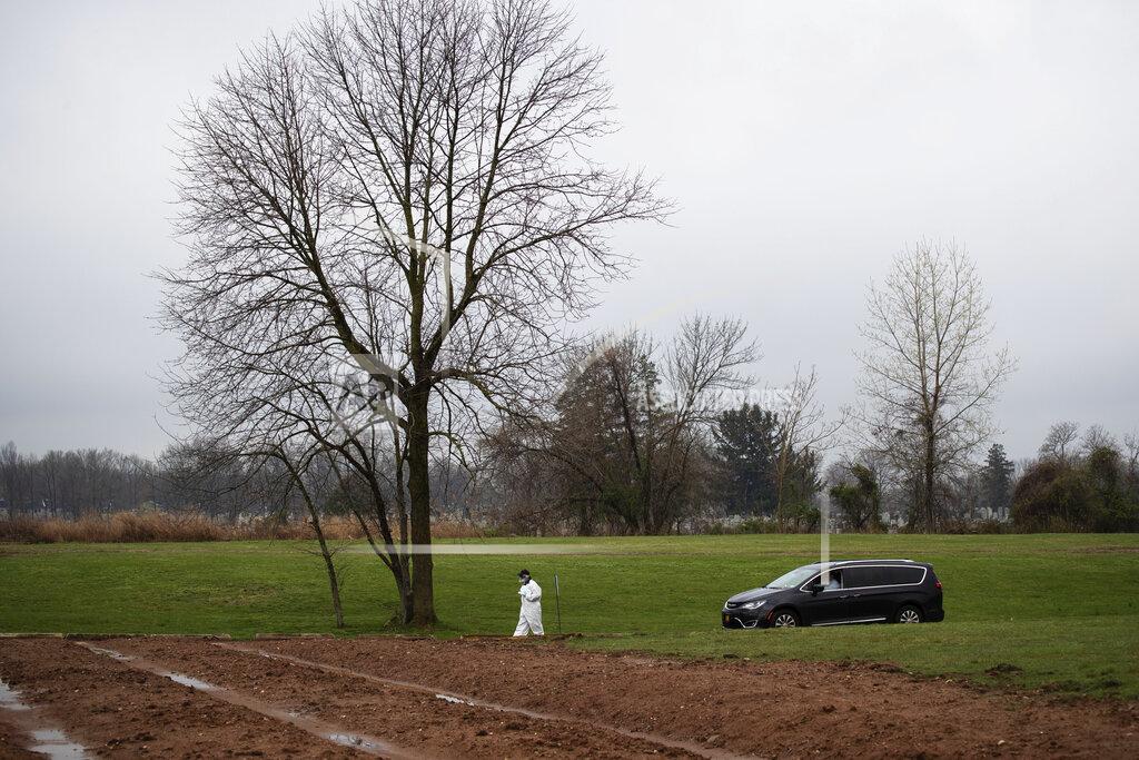 David Goldman Rabbi Shmuel Plafker escorts Michael Tokar to the plot for the burial of his father, David Tokar, at Mount Richmond Cemetery in the Staten Island borough of New York, Wednesday, April 8, 2020. Between travel restrictions and potentially exposed family members kept in isolation, many funerals now have no mourners on site. When they do, they are prohibited from gathering at the graveside, instead listening to rushed services by phone from cars parked 50 feet away. (AP Photo/David Goldman)