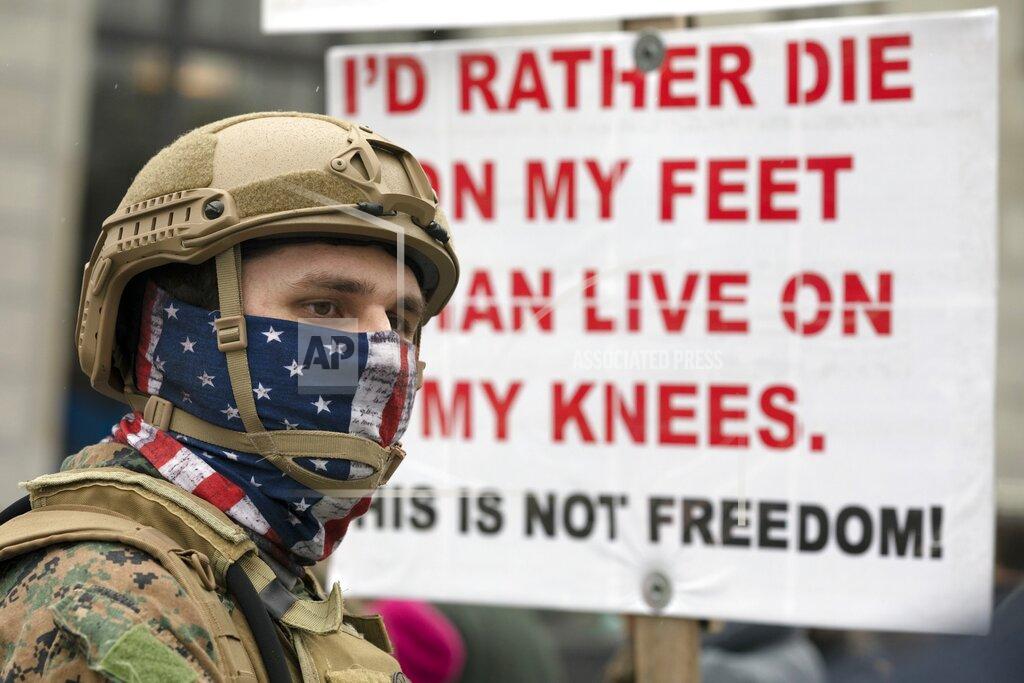 Michael Dwyer A man wears combat gear during a demonstration against the government mandated lockdown due to concern about COVID-19 at the State House, Saturday, April 18, 2020, in Concord, N.H. (AP Photo/Michael Dwyer)