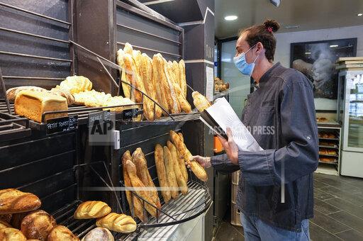 Baker Hugo Hardy prepares baguettes to be sold at Bigot bakery in Versailles, west of Paris, Tuesday, Oct. 26, 2021. A worldwide increase in wheat prices after bad harvests in Russia is forcing French bakers to raise the price of that staple of life in France the baguette. Boulangeries around France have begun putting up signs warning their customers of an increase in the price of their favorite bread due to rising costs. (AP Photo/Michel Euler