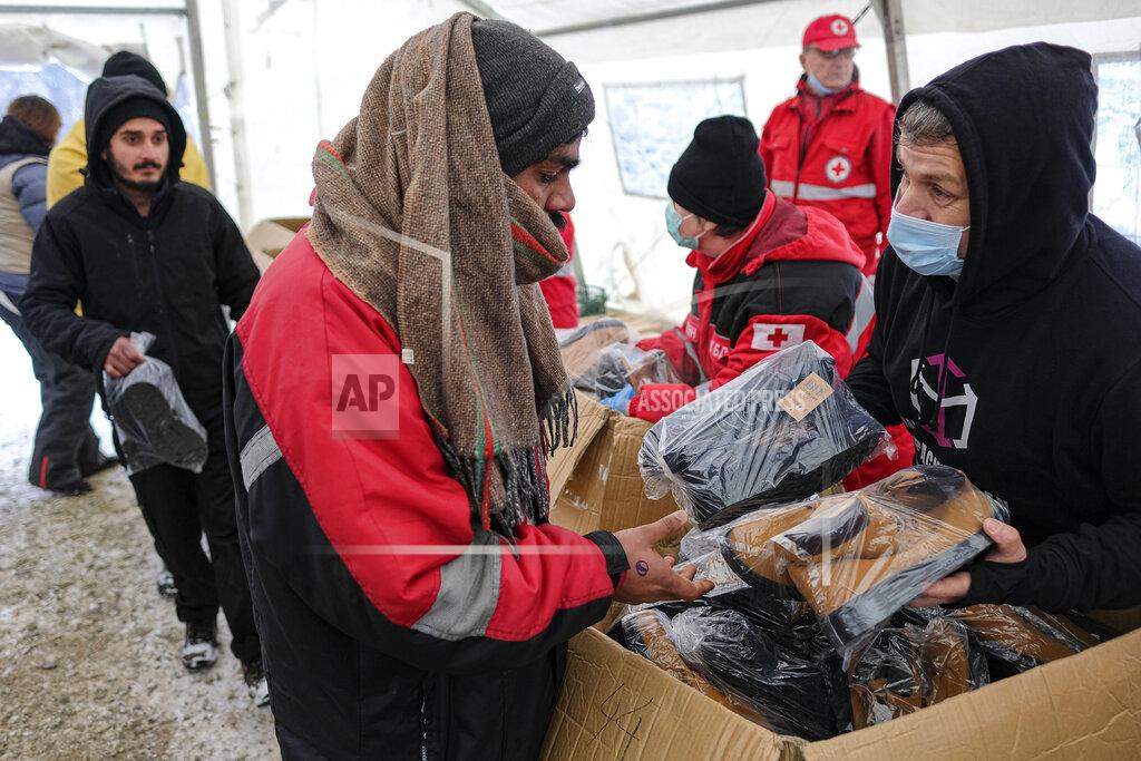Kemal Softic Migrants receive footwear and blankets from a humanitarian organization at the Lipa camp, outside Bihac, Bosnia, Monday, Jan. 11, 2021. Aid workers say migrants staying at a camp in northwestern Bosnia have complained or respiratory and skin diseases after spending days in make-shift tents and containers amid freezing weather and snow blizzards. Most of the hundreds of migrants at the Lipa facility near Bosnia's border with Croatia on Monday have been accommodated in heated military tents following days of uncertainty after a fire gutted most of the camp on Dec. 23. (AP Photo/Kemal Softic)