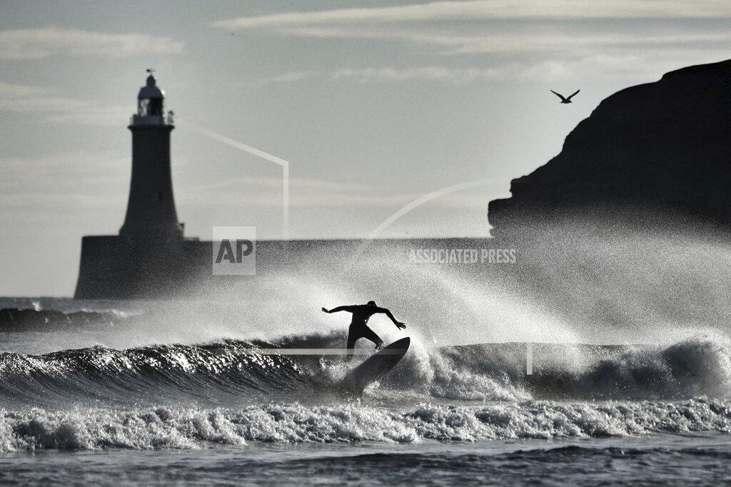 Owen Humphreys A surfer silhouetted against the waves at Tynemouth, near North Shields, England, Thursday Nov. 12, 2020. Clear Autumn weather has settled across much of England. (Owen Humphreys/PA via AP)