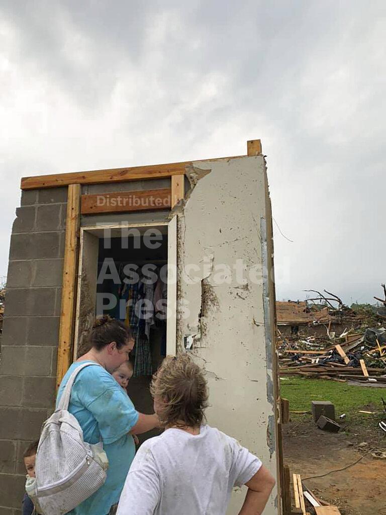Amber Phillips stands outside the family's safe room, located on their property in Moss, Miss., following a tornado, Monday, April 13, 2020. While the rest of their home was obliterated in a matter of seconds Sunday afternoon, Phillips, her husband Andrew and their kids, ages 2 and 6 months, survived the storm without a scratch inside the small safe room, which doubles as a closet. (Andrew Phillips via AP)