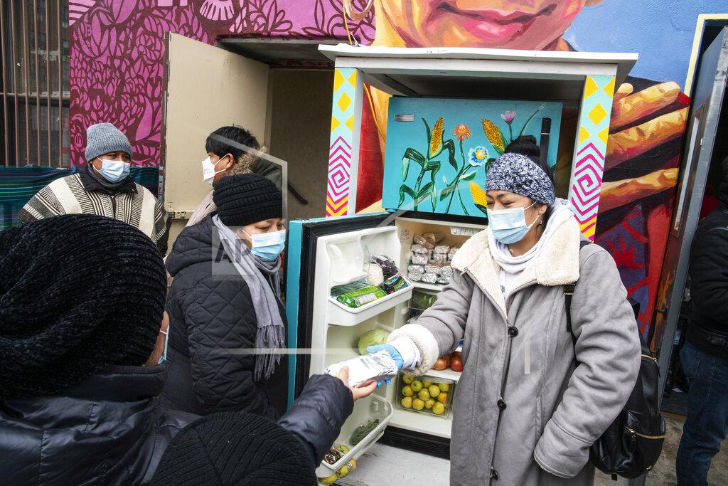 Eduardo Munoz Alvarez Volunteers pass out information on the COVID-19 vaccine as people receive food from the 24-hour community fridge at the community center Mixteca during the coronavirus pandemic, Saturday, Feb. 13, 2021, in the Brooklyn borough of New York. From elderly Cuban Americans in Florida to farmworkers in California, Latinos face daunting barriers like fear, language and a lack of education and access as the COVID-19 vaccines roll out, creating risks for public health as the virus mutates and spreads. (AP Photo/Eduardo Munoz Alvarez)