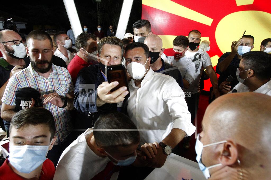 Boris Grdanoski The leader of the ruling SDSM party Zoran Zaev, center right, wearing a mask as he is pose for a selfie after his victory at the North Macedonia general election, in Skopje, early Tuesday, July 16, 2020. A suspected hacking attack caused the site of North Macedonia's electoral commission to crash for hours after polls closed in the country's national elections Wednesday, delaying preliminary results that showed the Social Democrats narrowly leading the center-right opposition.(AP Photo/Boris Grdanoski)
